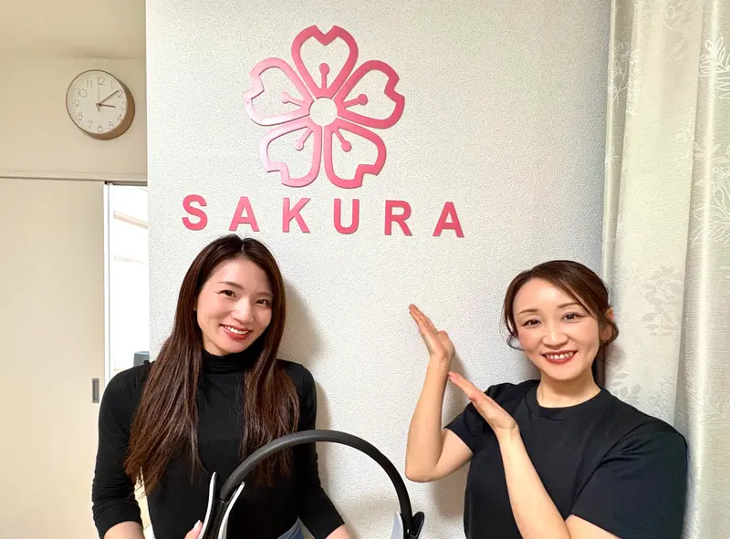SAKURA　ロゴの前で